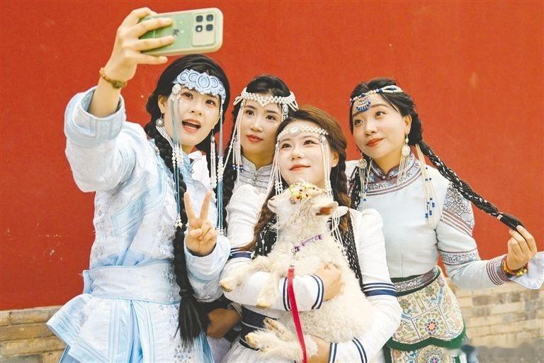 请到醉美草原来遇见美好 近日，在呼和浩特大召广场，游客身着民族服饰打卡拍照。目前