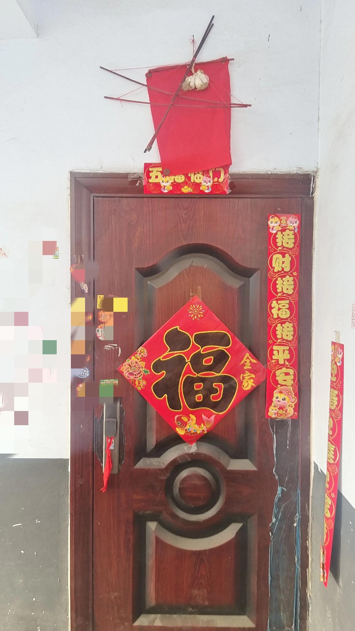 今天早晨开门，抬头一看，只见对门邻居家的门口上方挂了一块红布，几根红色高粱杆，还