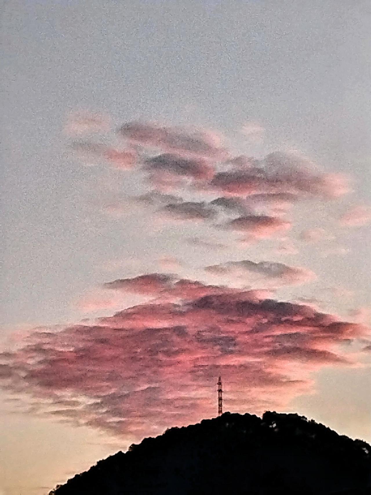 山头塔影入云霞，夕照红霞映晚霞。夕阳西下的时候，云朵在光的照射下变幻出色彩，有的