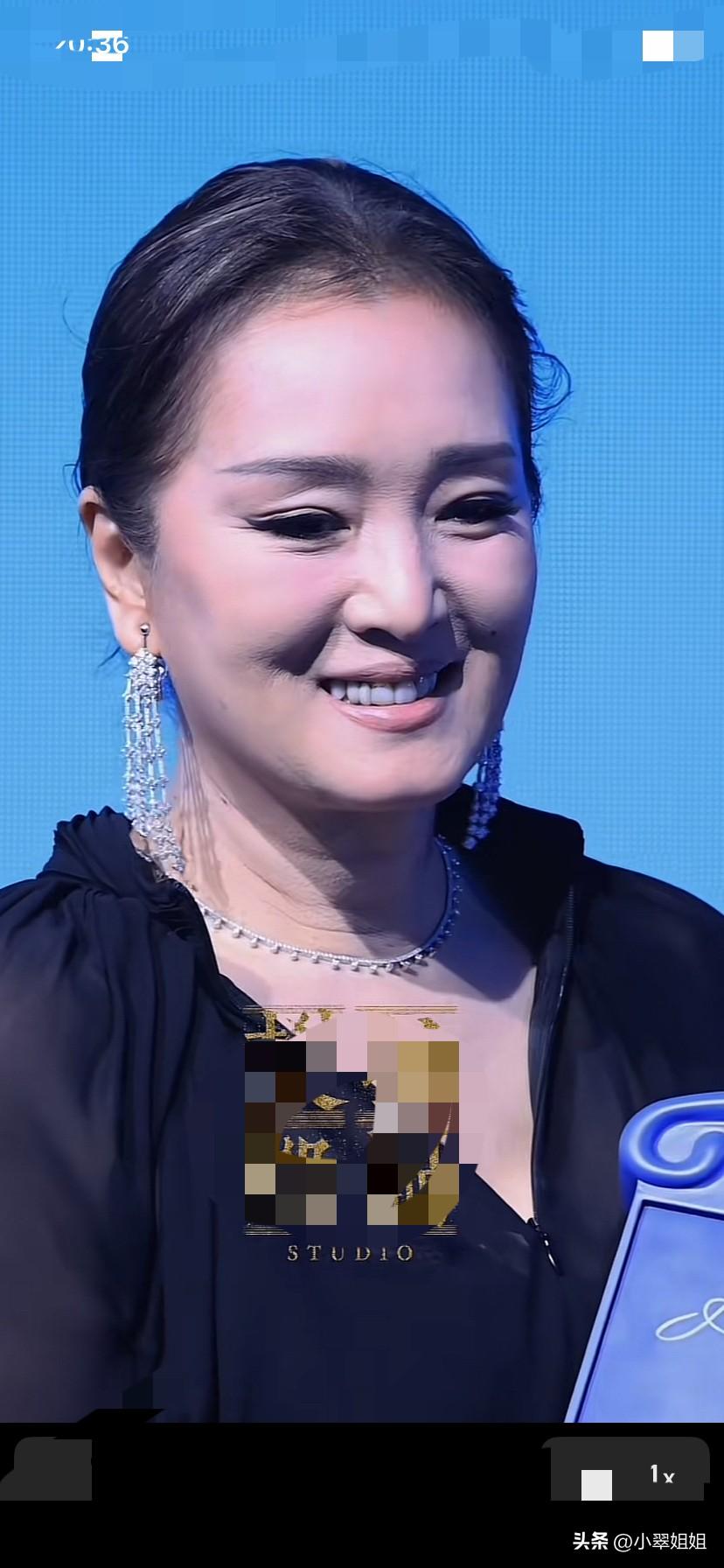 巩俐毕竟也是61岁的老年人了！头顶隐约也有一丝丝白发了！眼线画的非常重，脖颈上皱
