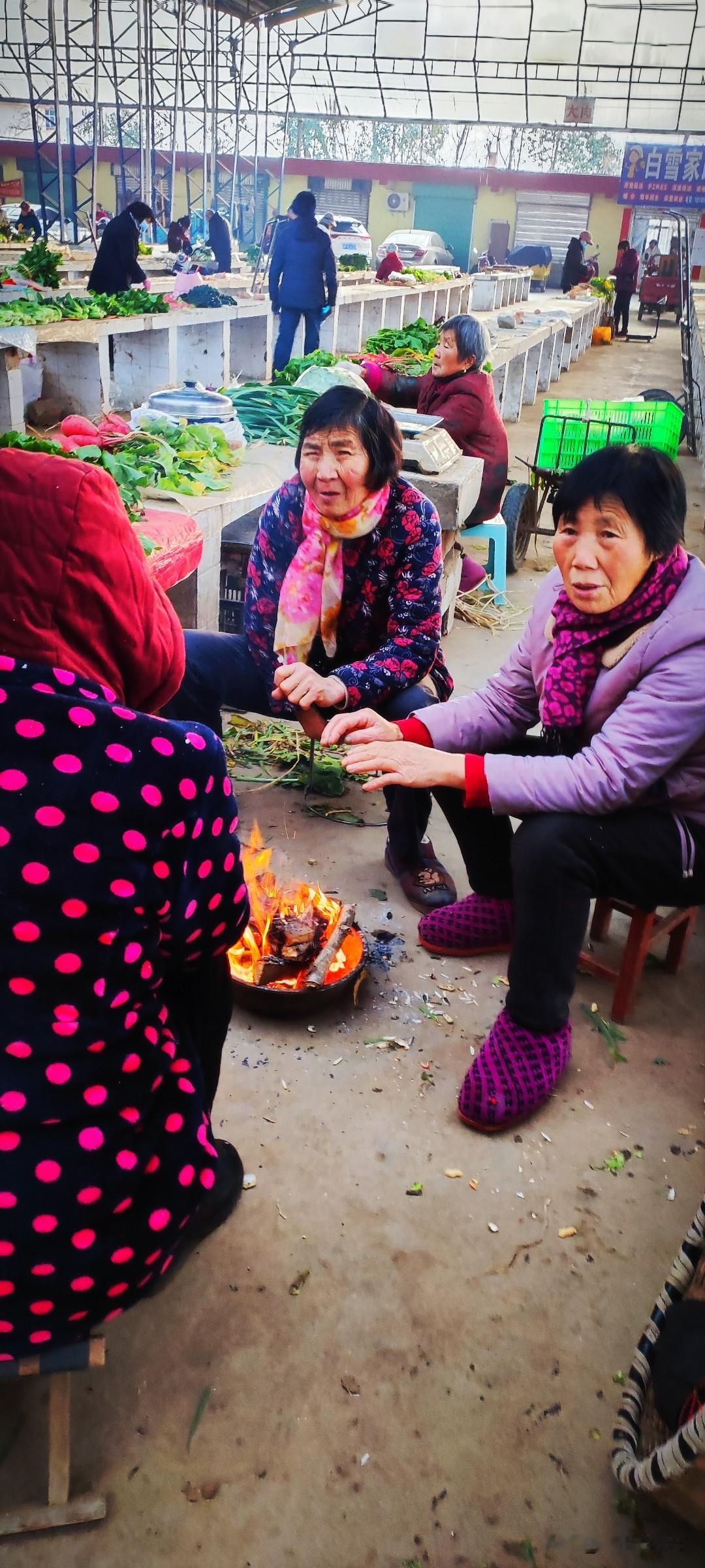一张图证明冬天来了农贸市场里面的摆摊大妈们聚在一起，“歇火”是本地方言里“烤火”
