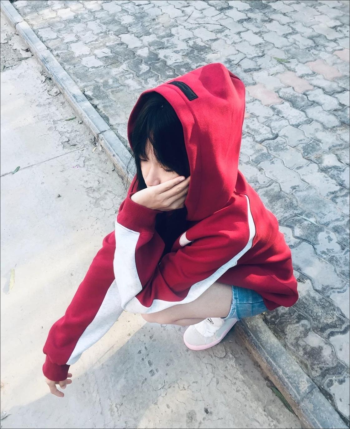 红衣少女蹲坐街边，黑发遮面，若有所思。
