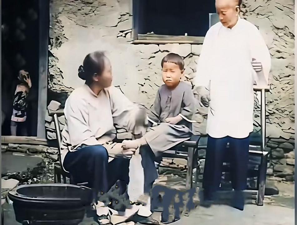 下图的照片是民国母亲为女儿裹小脚的画面，时间是1930年，地点是湖北武昌，照片拍