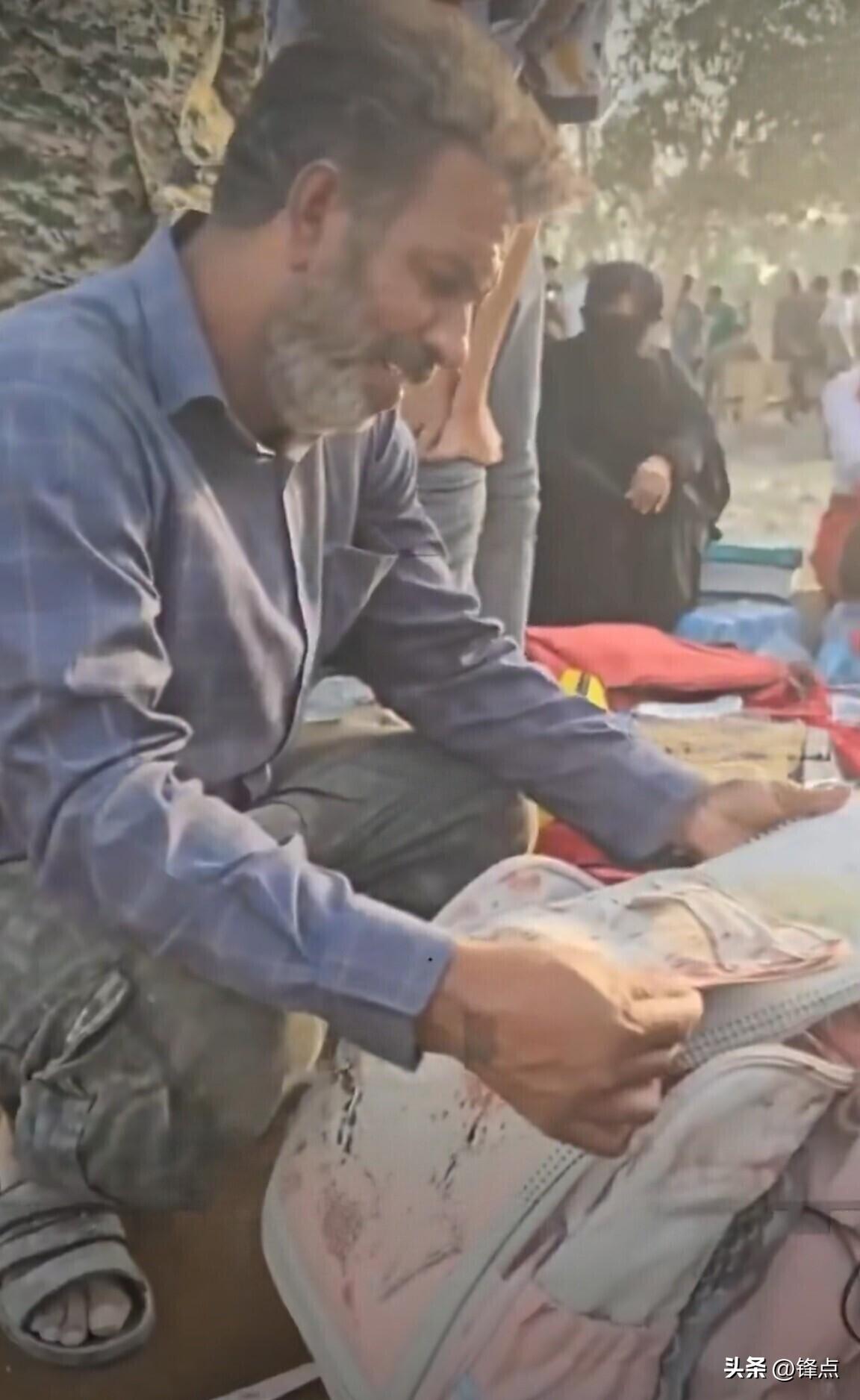 一位伊朗家长翻找遇难女儿带血的书包。

近日，一段令人心碎的视频在网络上热传。视