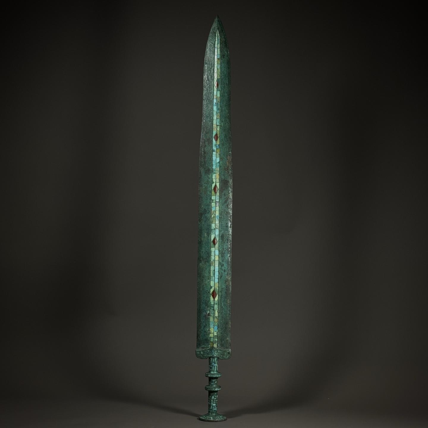 青铜剑。这柄青铜嵌绿松石剑，剑身以松石、红宝错嵌纹饰，工艺卓绝。青铜氧...