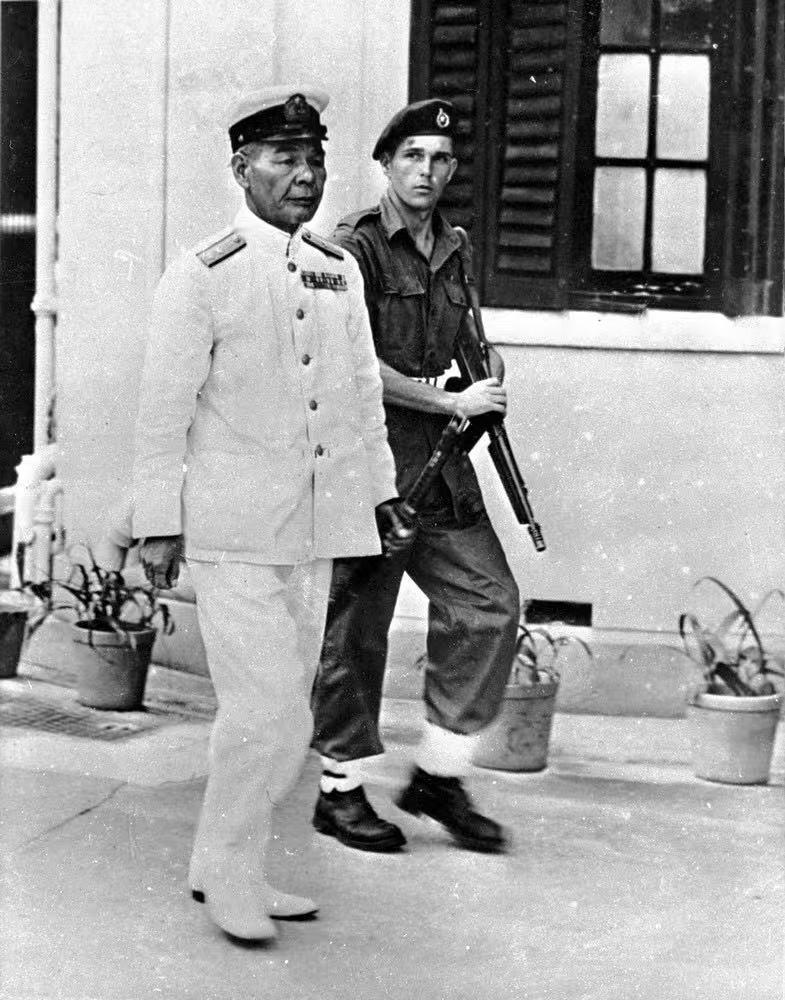 图一：1945年9月16日，日本海军中将藤田瑞太郎在英军皇家海军陆战队队员押送下