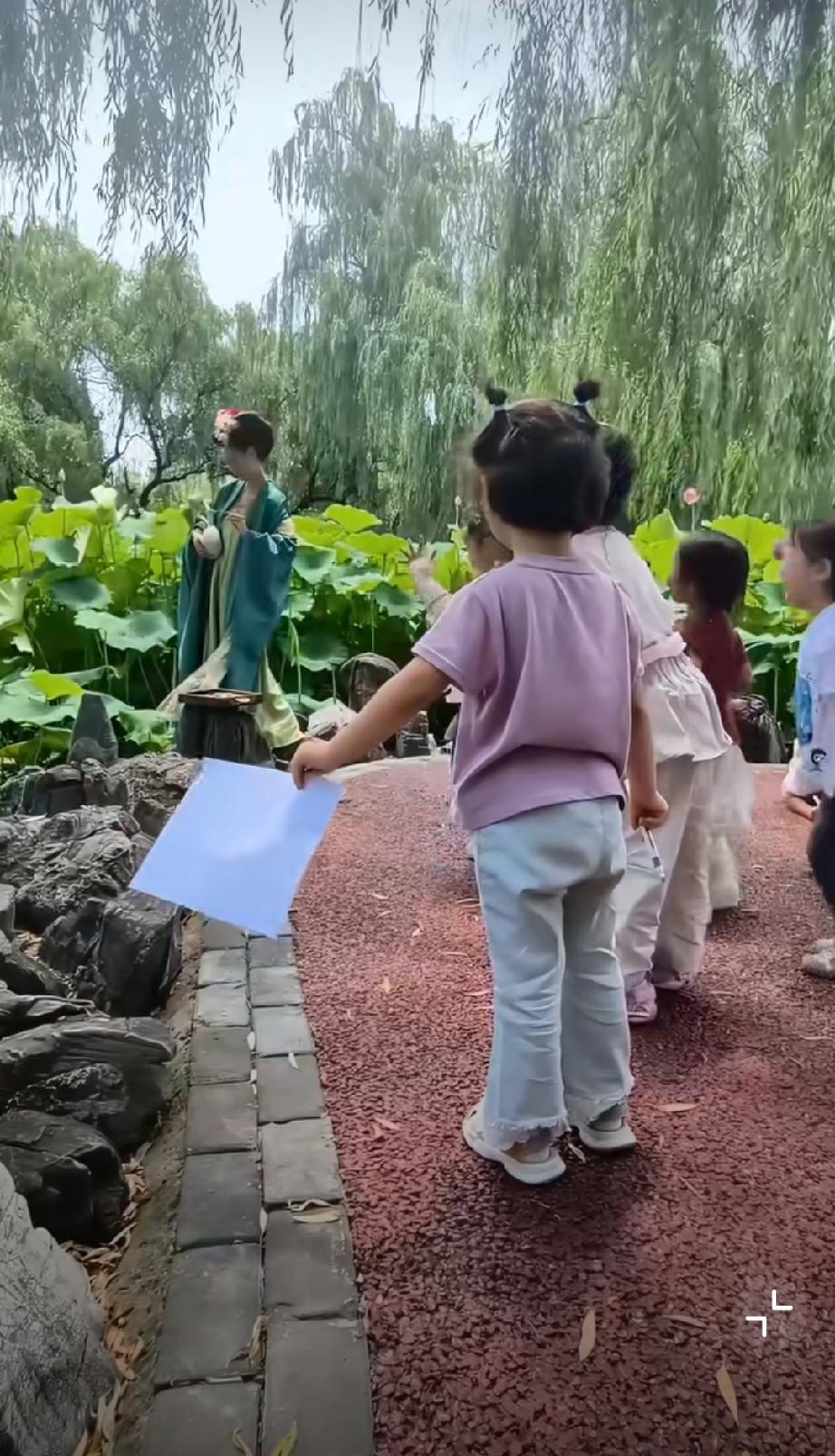 女子穿汉服拍照被小朋友围观欢呼雀跃。美，是一种被看见的欢喜，惟有绿荷红菡萏，卷舒