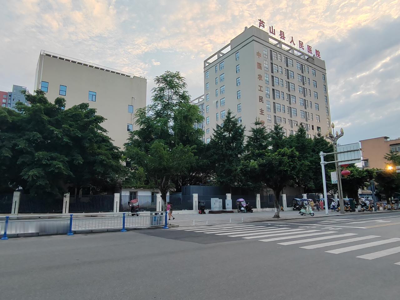暮色漫过芦山街头，天边云彩晕开温柔霞光，道旁绿树葱郁，斑马线延伸向烟火街巷。这里