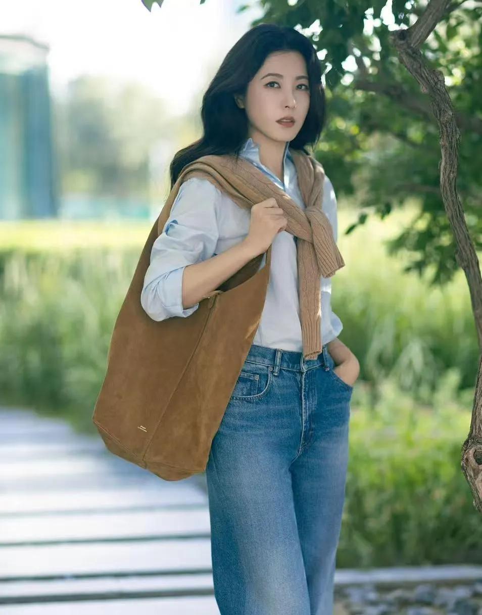 48岁曾黎的中年穿搭，把松弛感拿捏了✨
 
浅蓝色衬衫+驼色针织衫随意搭在肩上，