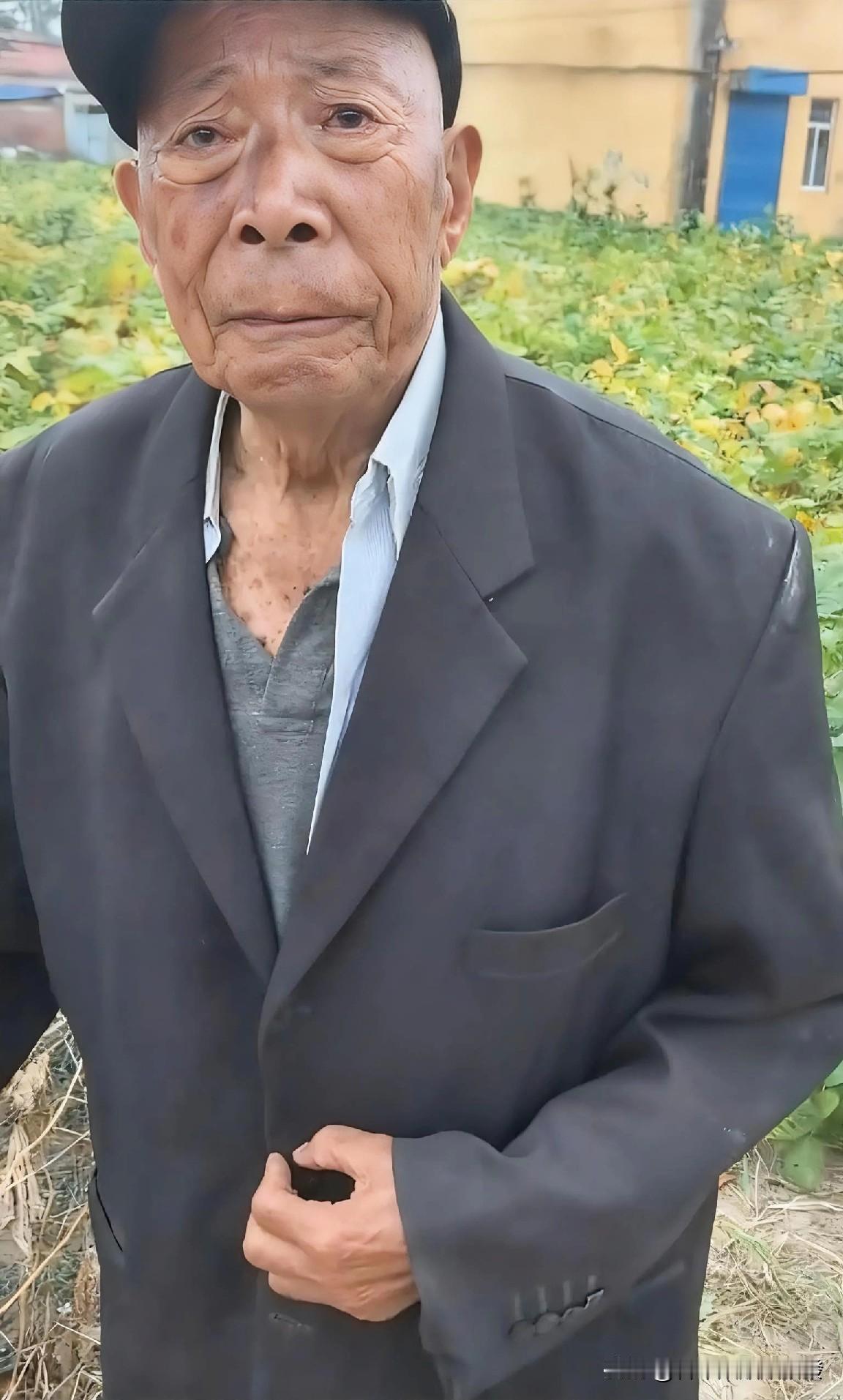 老人一手扶着水泥石桩，一手拄着拐杖站在村口。他眼巴巴望着路上的一队人，渐渐陷入了