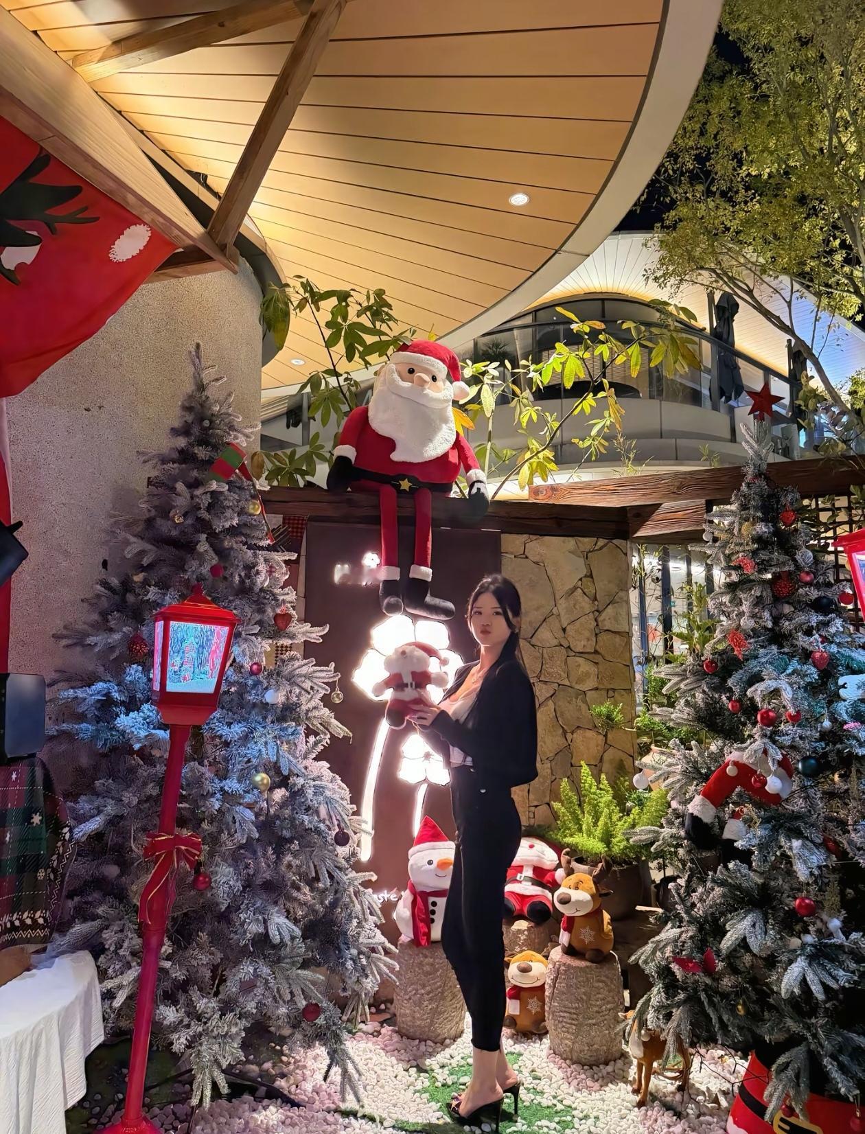 圣诞气氛浓，美女在圣诞树前拍照。