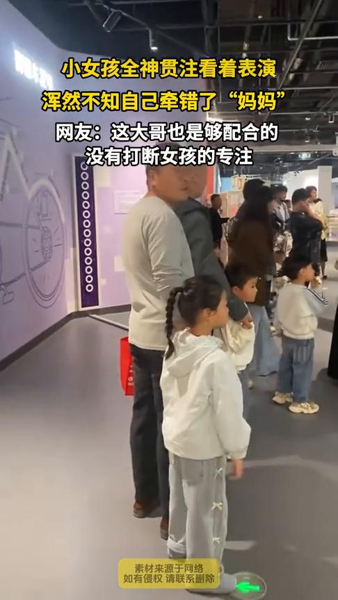 小女孩全神贯注看着表演，浑然不知自己牵错了"妈妈"。网友：这大哥也是够配合的，没