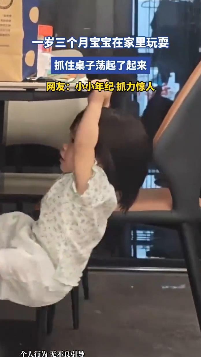 一岁三个月宝宝在家里玩耍，抓住桌子荡起了起来。网友：小小年纪抓力惊人。
6月24