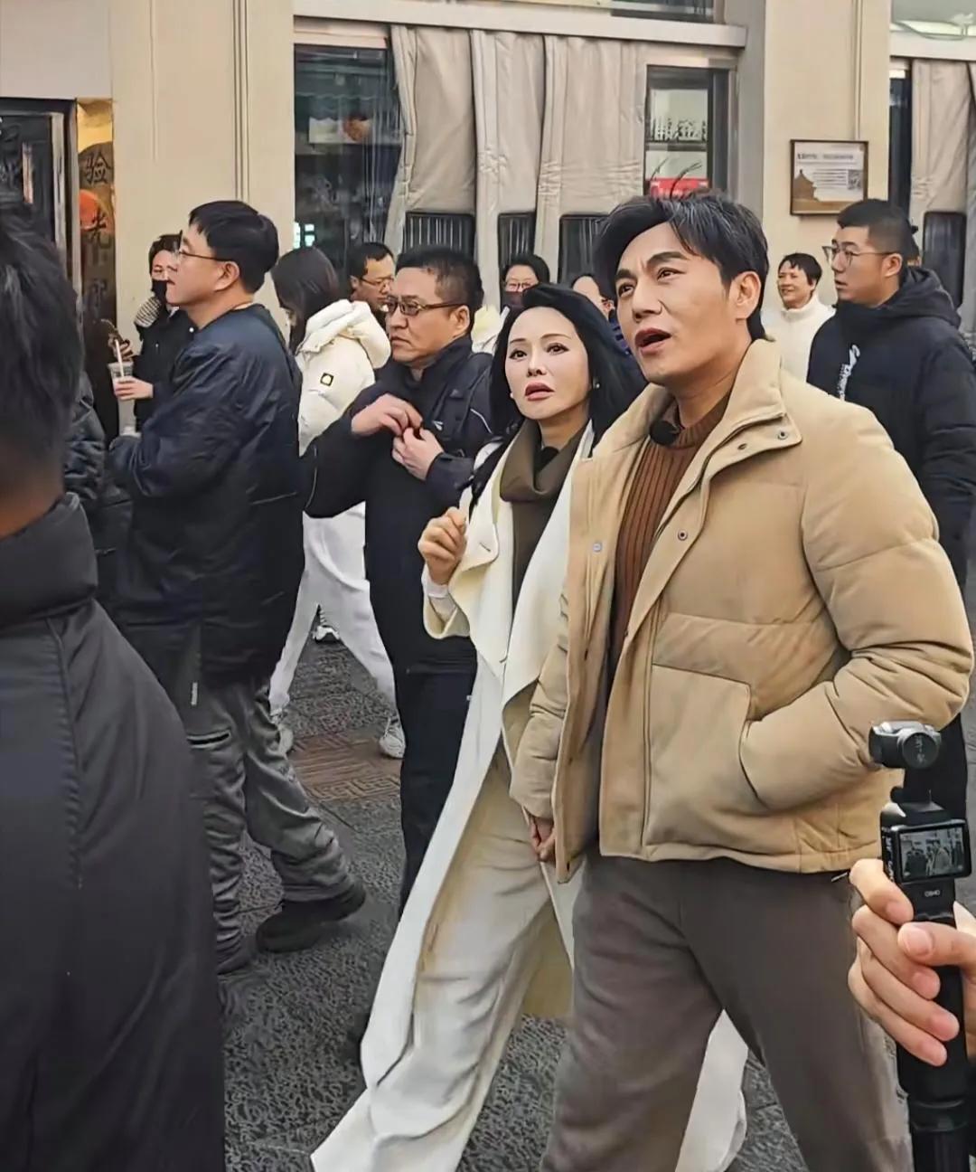 秦昊和老婆伊能静现身沈阳街头逛街，秦昊穿着浅黄色羽绒服，梳着三七分发型，身材又高