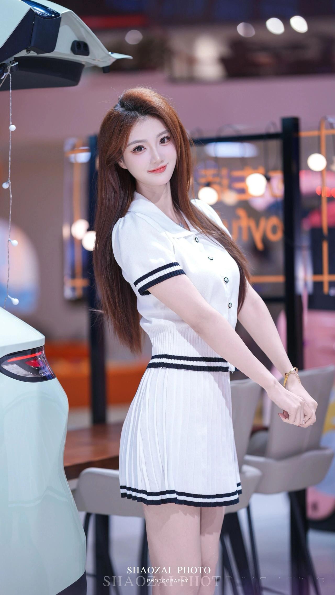 这位车展模特颜值与气质双在线，身着黑白撞色针织短款套装，修身版型搭配百褶短裙，尽