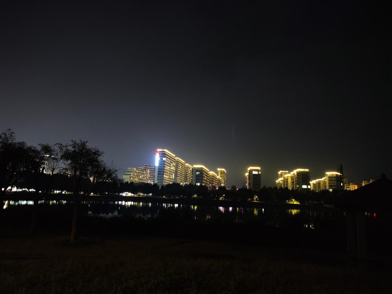 分享一张最美的湖面照片这是一张夜晚城市水景照片，对岸楼宇灯光亮起点点，灯光映入平