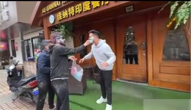 一群印度人在南京印度餐厅门口旁若无人地过洒红节，互相涂抹着彩粉的画面，路人看了不