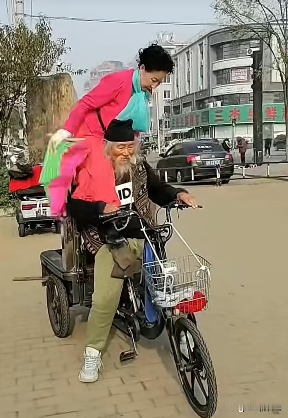 80岁老头骑着三轮电动车，60岁大妈骑在他脖子上扭秧歌，关键老头还把电动车打着火