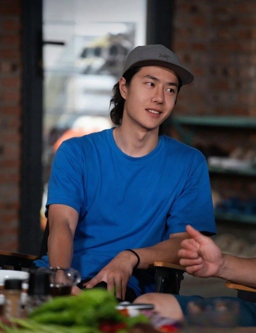藏在烟火气里的王一博，比聚光灯下更动人。宝蓝色T恤衬得眉眼干净，反戴的帽子遮不住