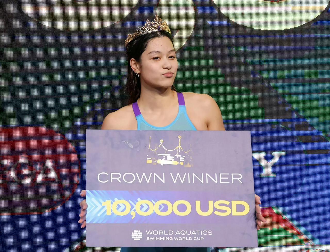 短池游泳世界杯上，游泳冠军余依婷戴上皇冠，拿着奖金赛，调皮地嘟了一下嘴，既可爱又