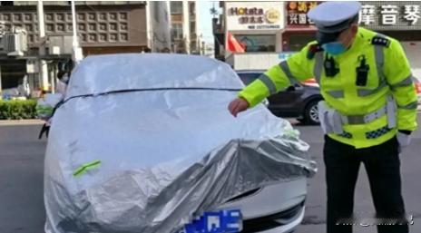 北京，一男子将车停在路面，并将车用车罩盖住。可当交警看到后以故意遮挡号牌为由扣1