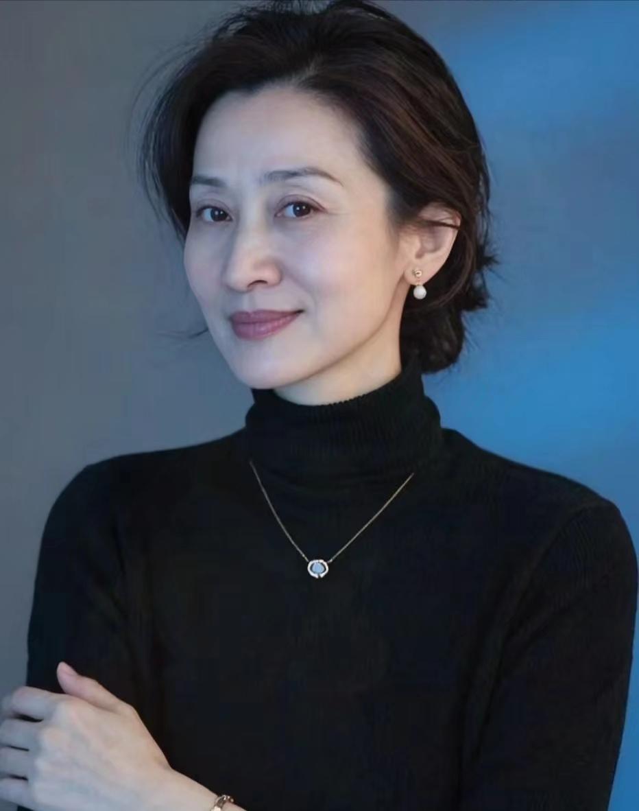 上联：素衣高领涵温润，颈间珠辉映雅韵
下联：短发轻挽蕴从容，耳畔珰色添清姿