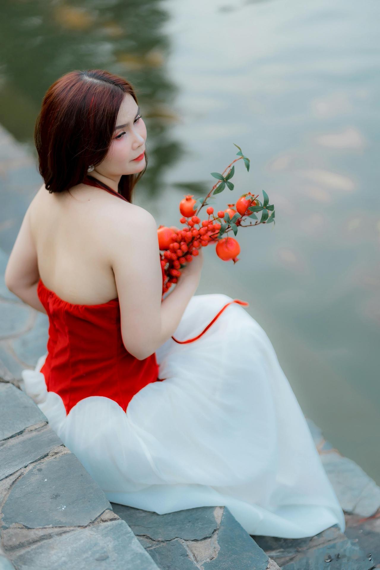 红裙曳着微风，
攀过木栏与池边的光影。
手心里攥着石榴的热烈，
又轻碰荷瓣的柔，