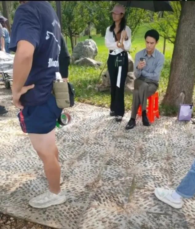 当我在公园看到王凯坐在塑料凳子上休息时，旁边有一位女助理为他打着伞遮阳，让我感到