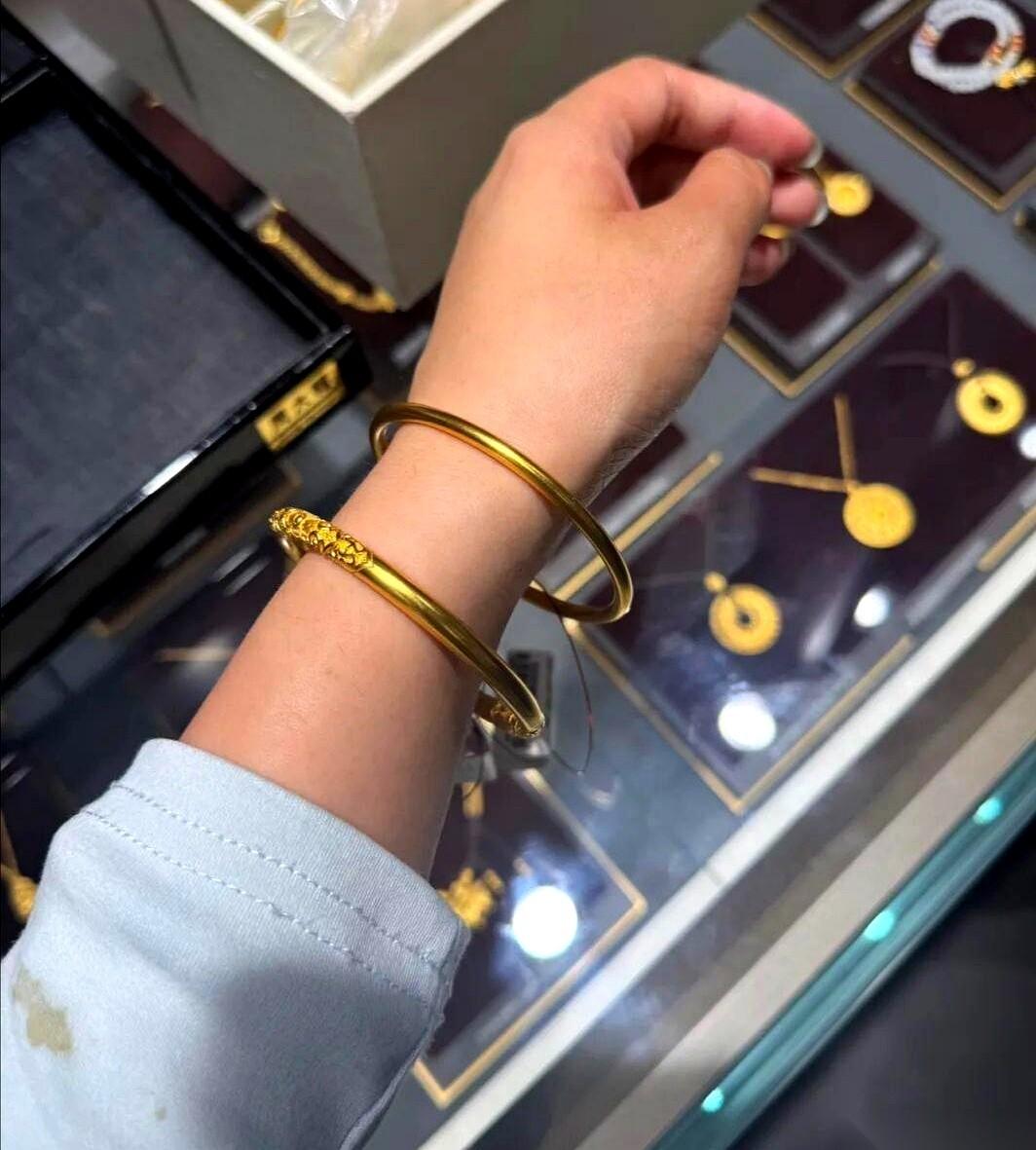 金店柜姐把两条镯子往丝绒盘上一推，顶上的射灯“嗡”一下全扎了上去。
左边那条，厚
