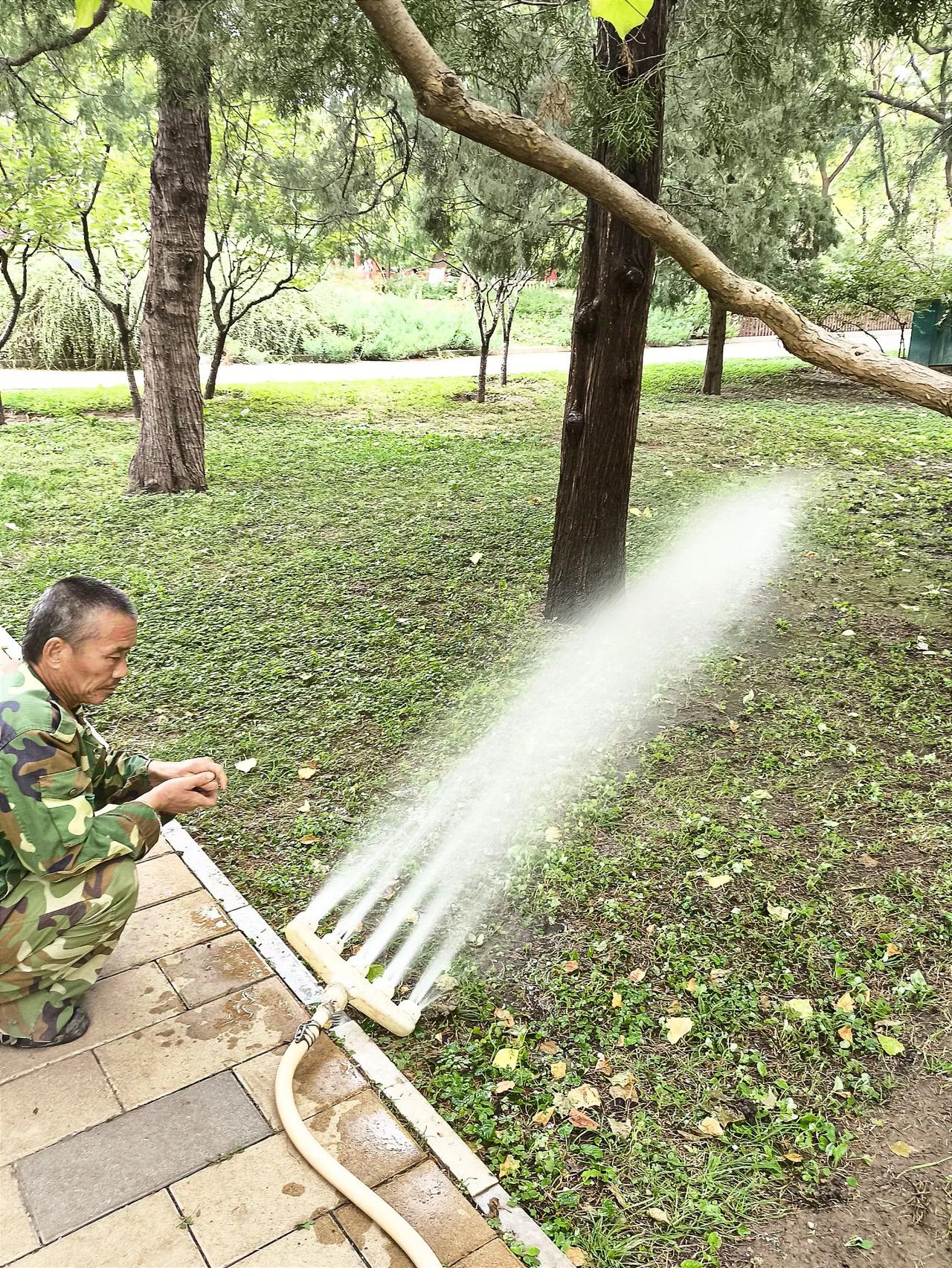 一位园林工人，在给树木和草地浇上冻前的最后一次水……