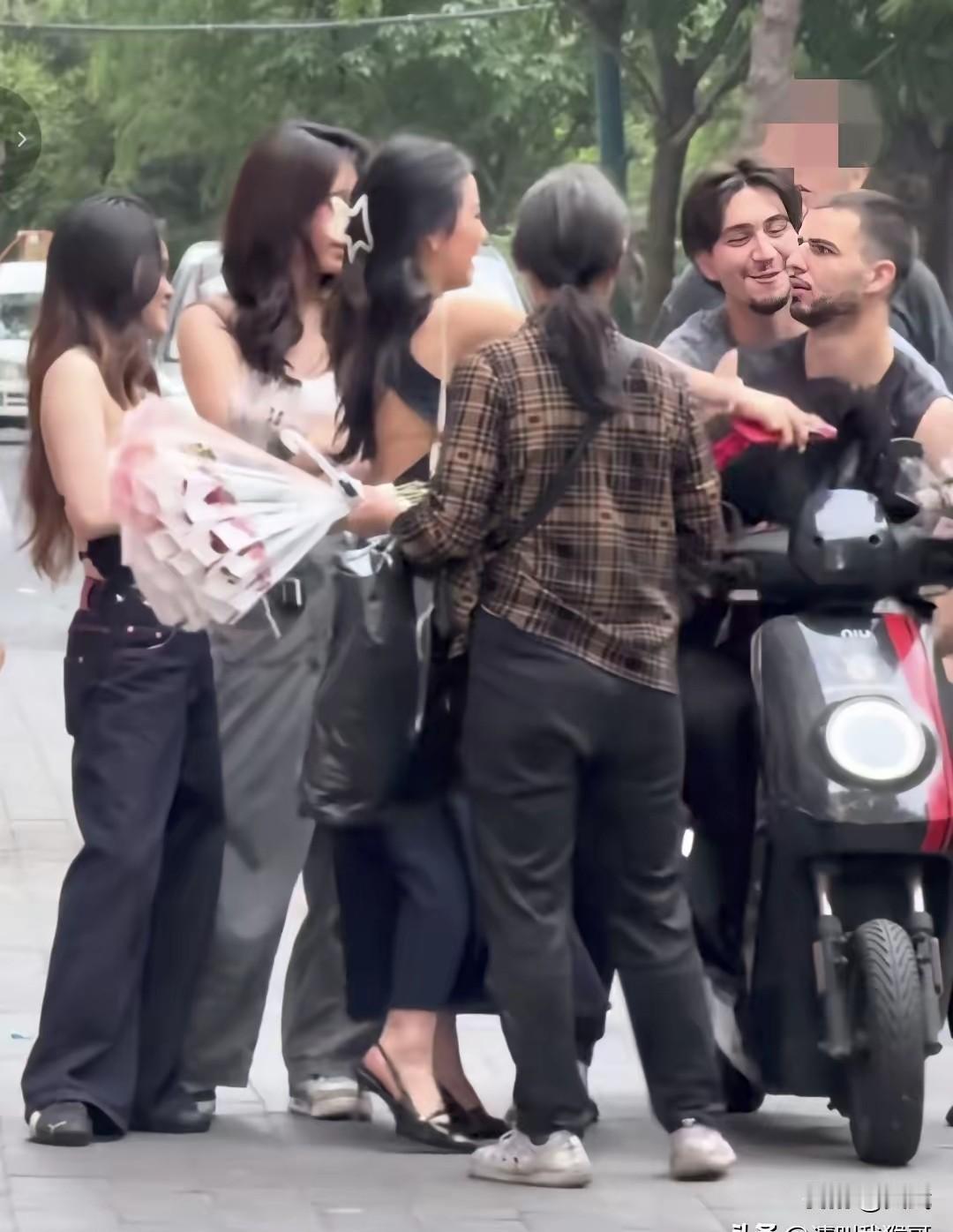 一个女孩捧着花追着老外递，对方摆手往后退，摆明了不想收，最后女孩硬把花塞到了人手