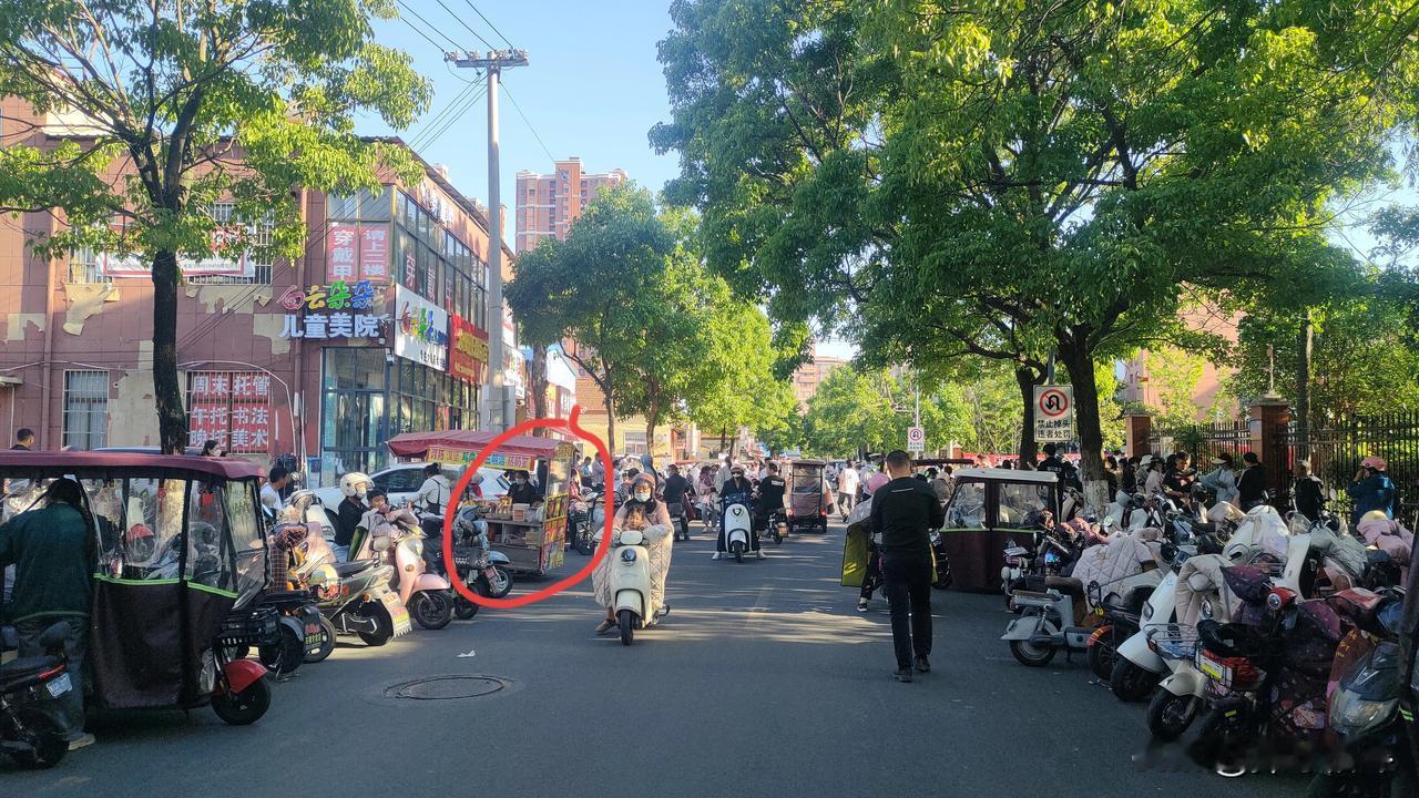 学生上学和放学的时间段两张图中的这几位摊主堵在路口堵在巷道口及路面上卖东西真的对