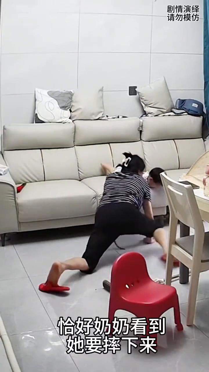 奶奶正在客厅打扫卫生，这时孙女在沙发上玩耍，恰好奶奶看到她要摔下来，幸亏奶奶反应