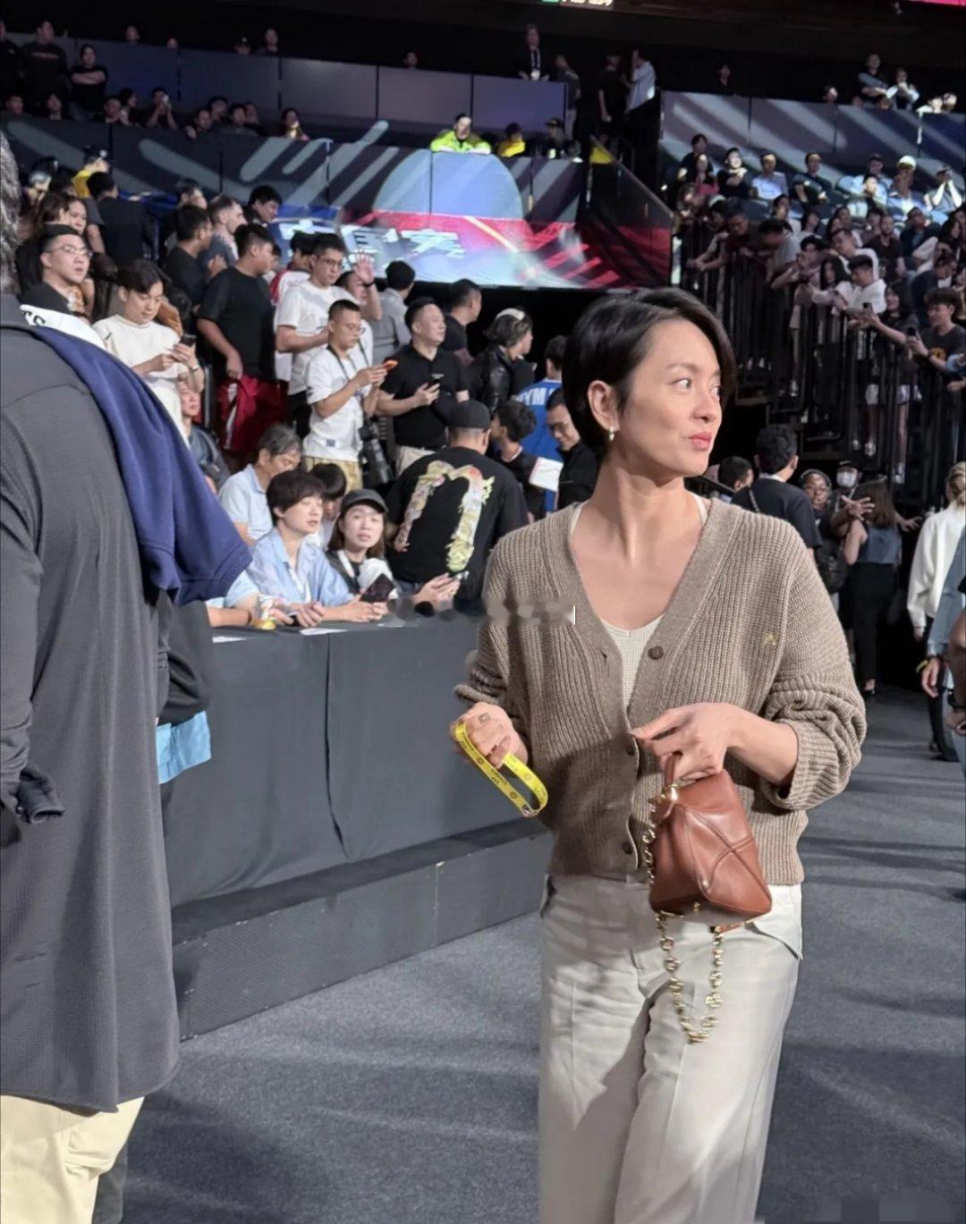 澳门NBA球赛上偶遇梁咏琪，本人又高又瘦很年轻。她身穿着浅灰色针织外套搭配白色裤