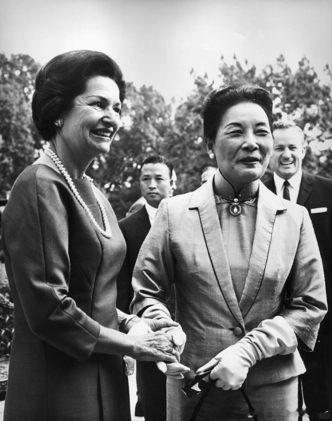 1965年，美国总统林登·B·约翰逊的夫人伯德·约翰逊在华盛顿白宫前握住宋美龄的