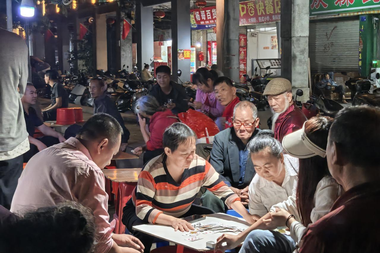 钦州街头夜晚的老年牌局｜钦州的夜晚，从来不止霓虹和车流。老榕树下牵起的电线挂着灯