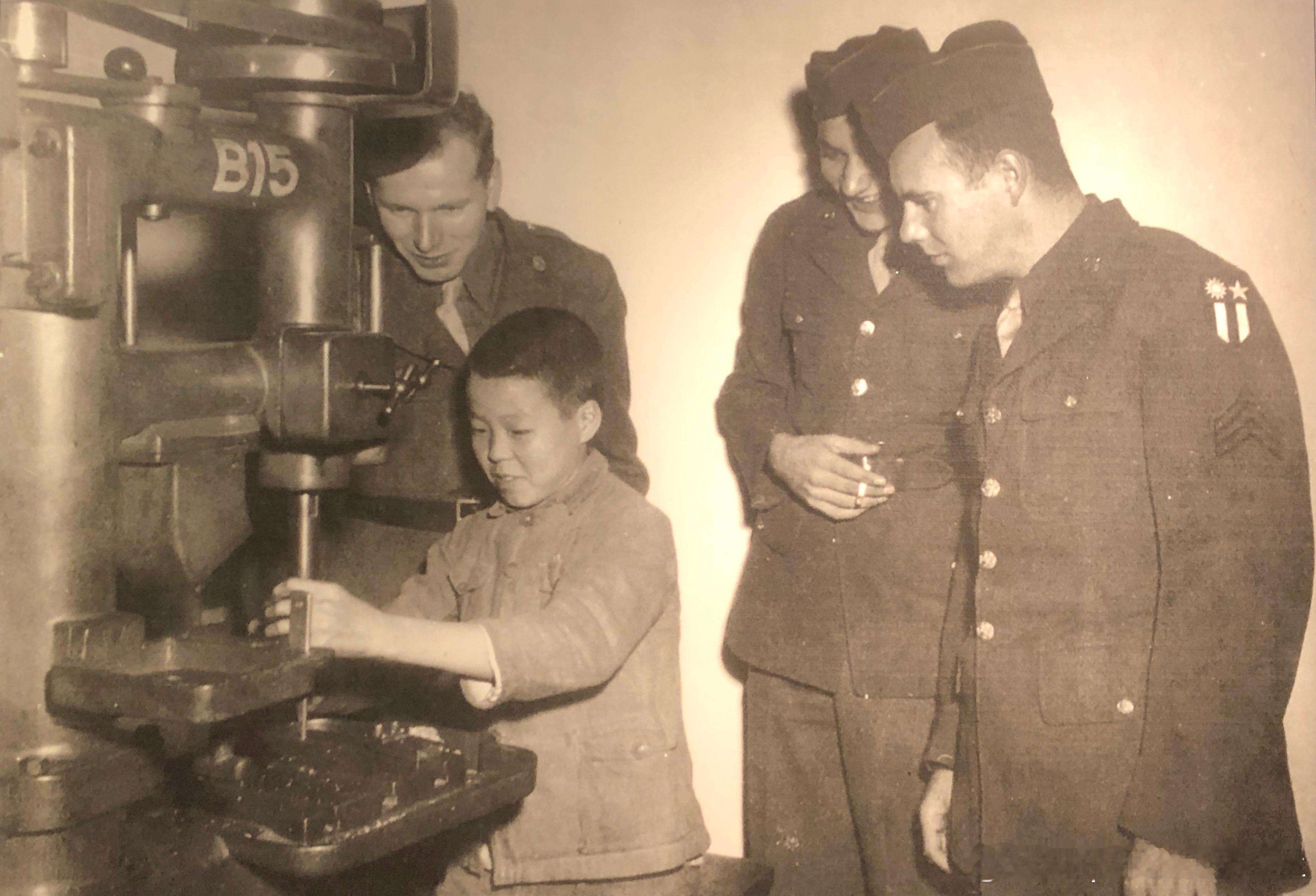 1943年6月美国士兵参观重庆一处兵工厂，一名男孩在演示操作钻床军事历史全触达 