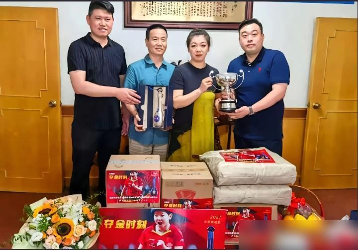 这是莎莎的爸爸，妈妈呀，手上还捧着奖杯，桌子上全是莎莎，还写着夺冠时刻四个大字。