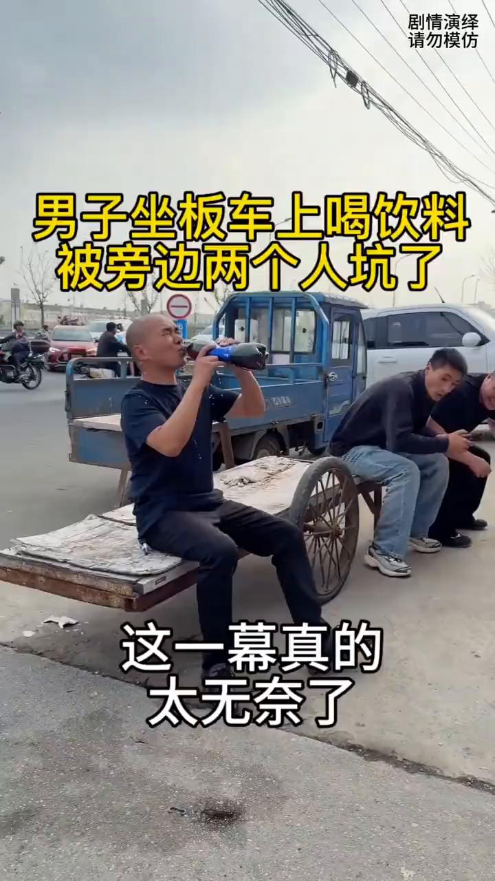 男子坐板车上喝饮料被旁边两个人坑了，这一幕真的太无奈了。
男子拿着一瓶饮料找地方