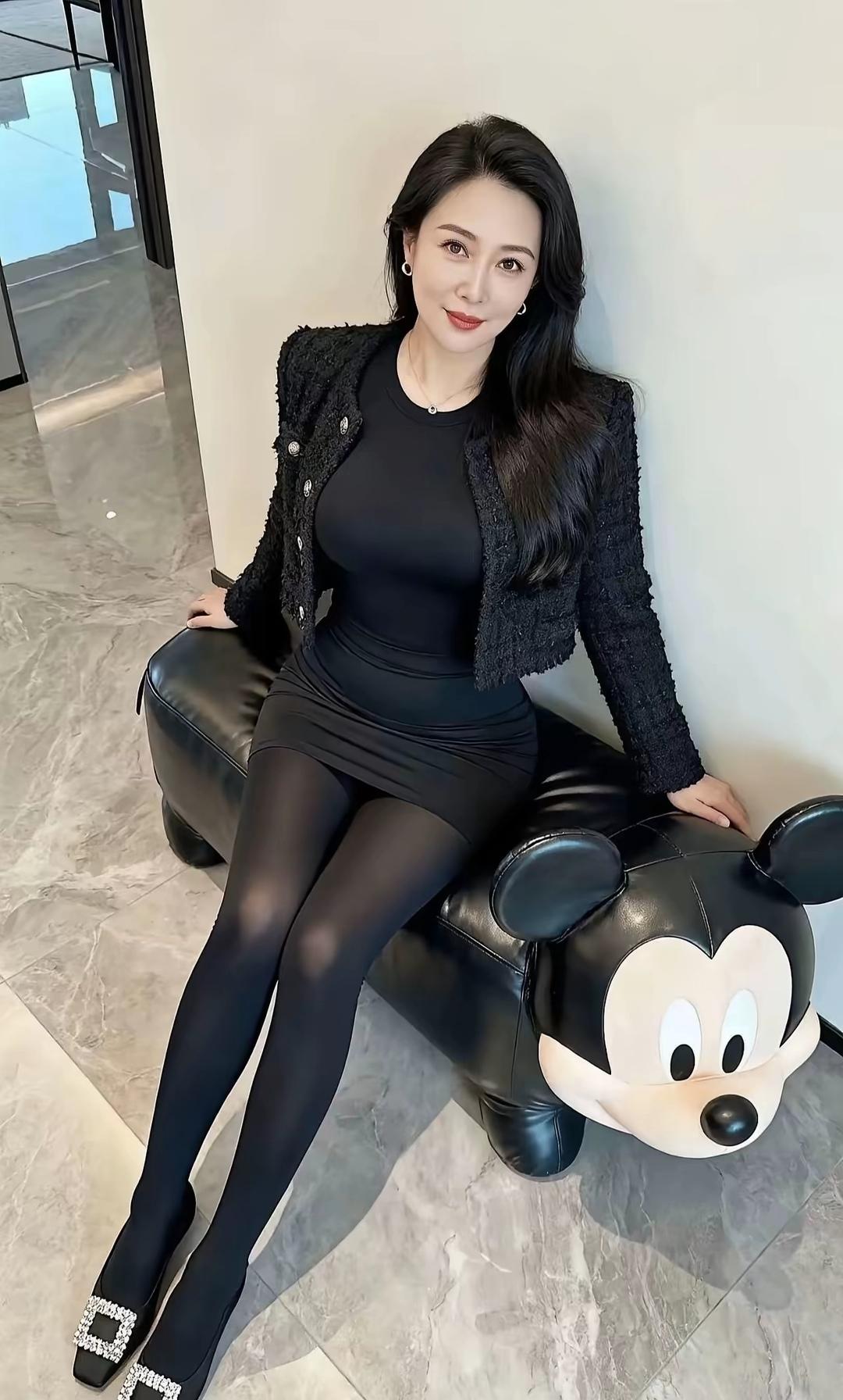 优雅黑裙搭配闪亮高跟鞋，坐在米奇头靠垫上，时尚又可爱