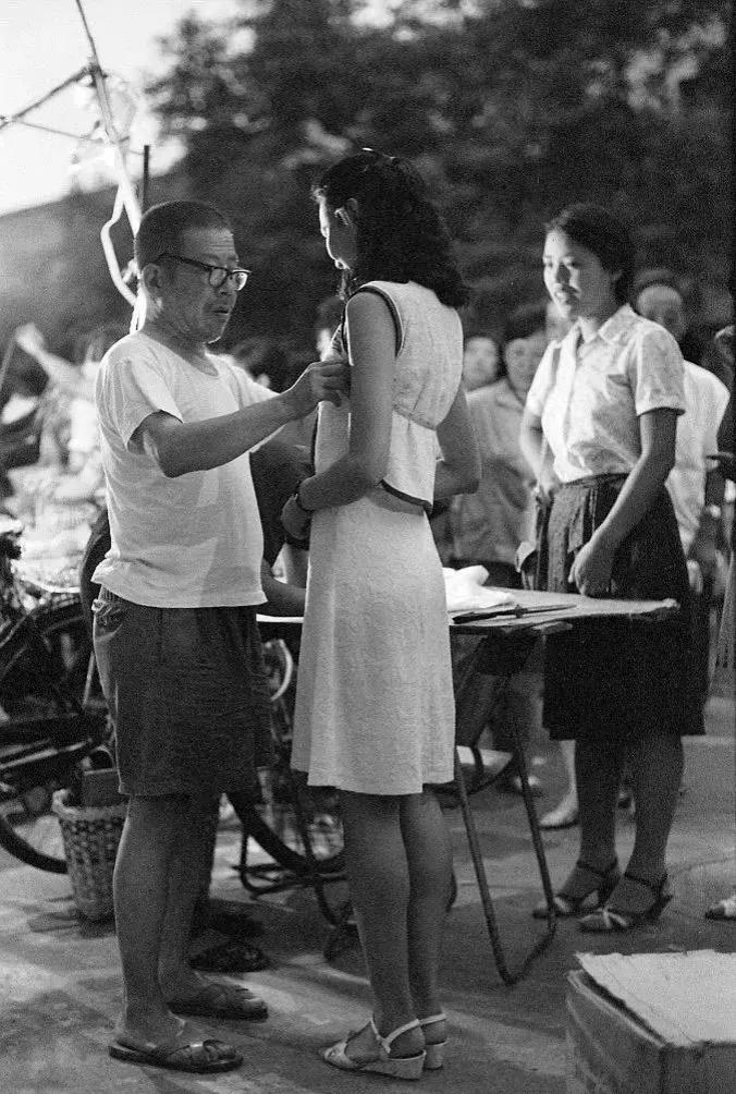 1984年，北京东华门夜市，裁缝师傅为顾客量体裁衣。