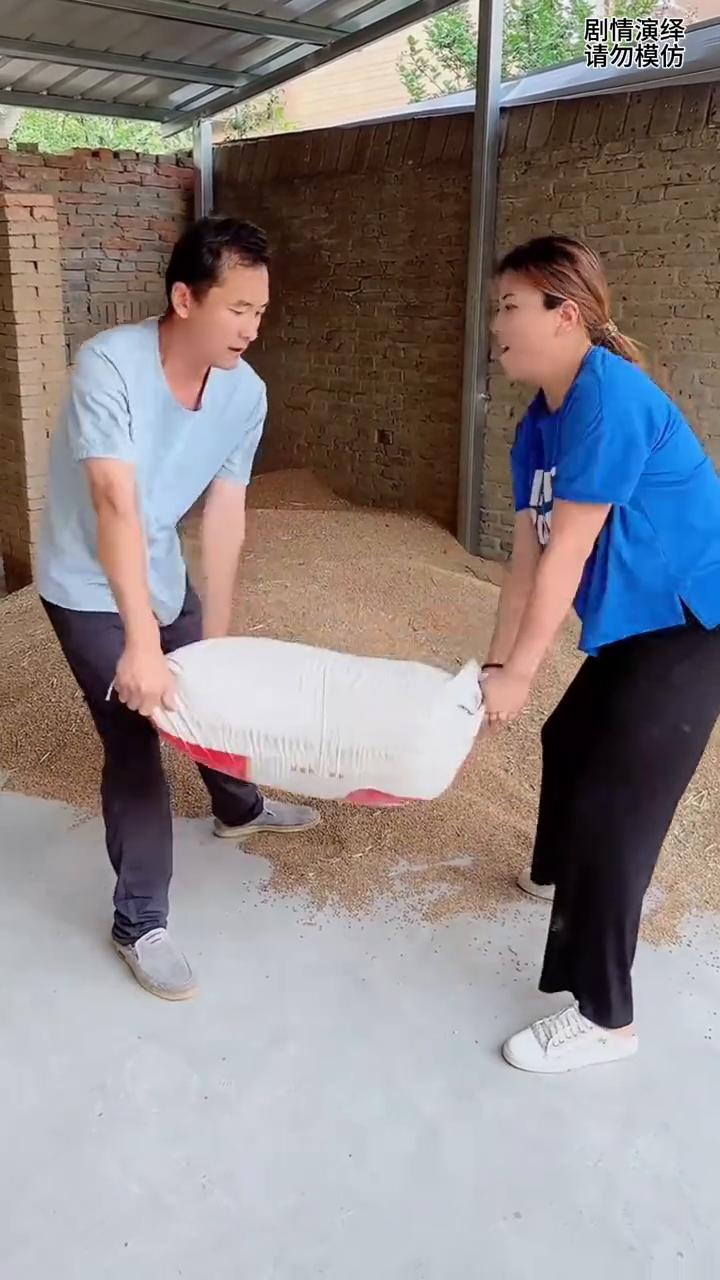 媳妇帮丈夫扛麦子却撒了一地，这一幕真的太无奈了。
男子准备扛走麦子，由于太重了他