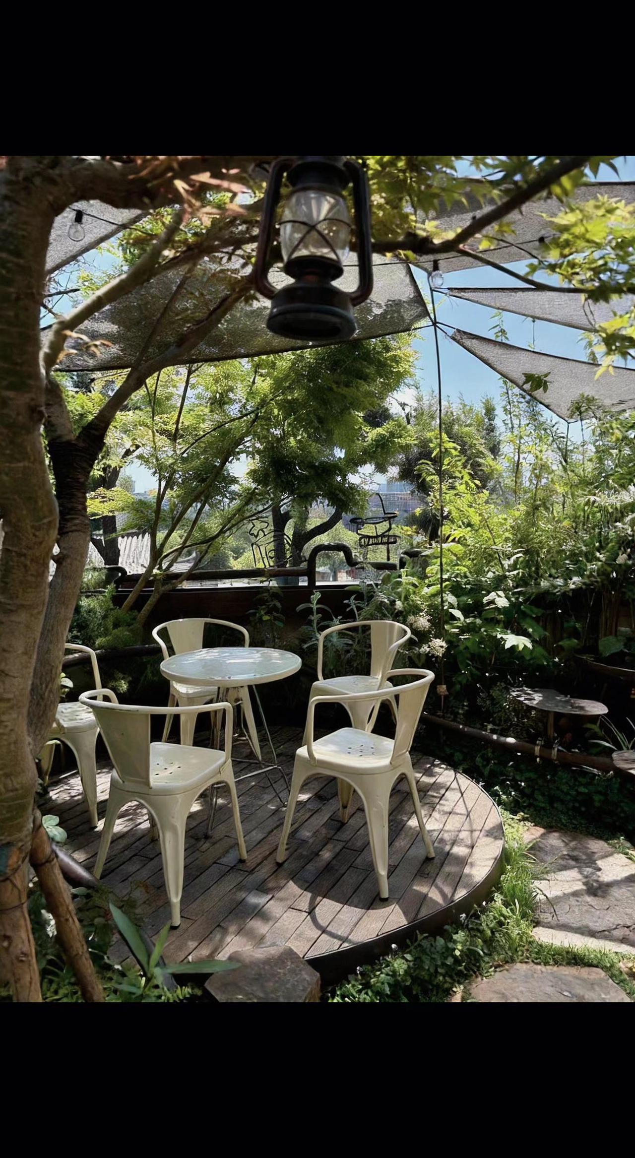 🌿灯笼在树影里打盹，桌椅等风来赴约🍃 偷得浮生半日闲，心在绿野仙踪里荡秋千～