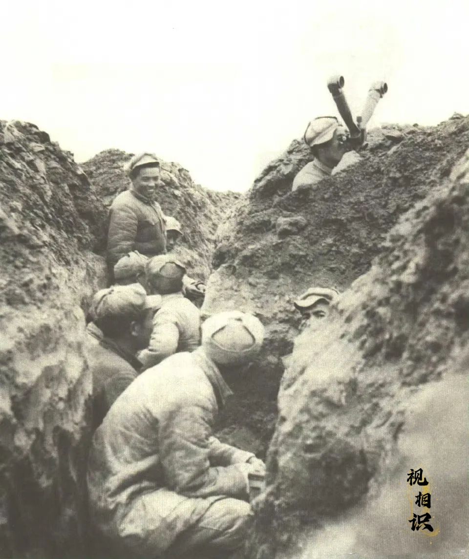 1948年12月，淮海战役后期，解放军战士在深邃的壕沟里围坐在一起。其中一位战士...
