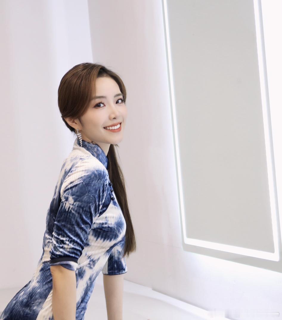 余霜 站在舞台中央，宛如一幅流动的画卷。蓝色印花旗袍，仿佛是江南水乡的温柔与细腻