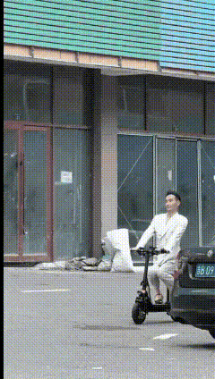 一个男人穿了一套白色的西服，脚上套了一双黄色的女袜子，脚下穿了一双黑色的女人拉带