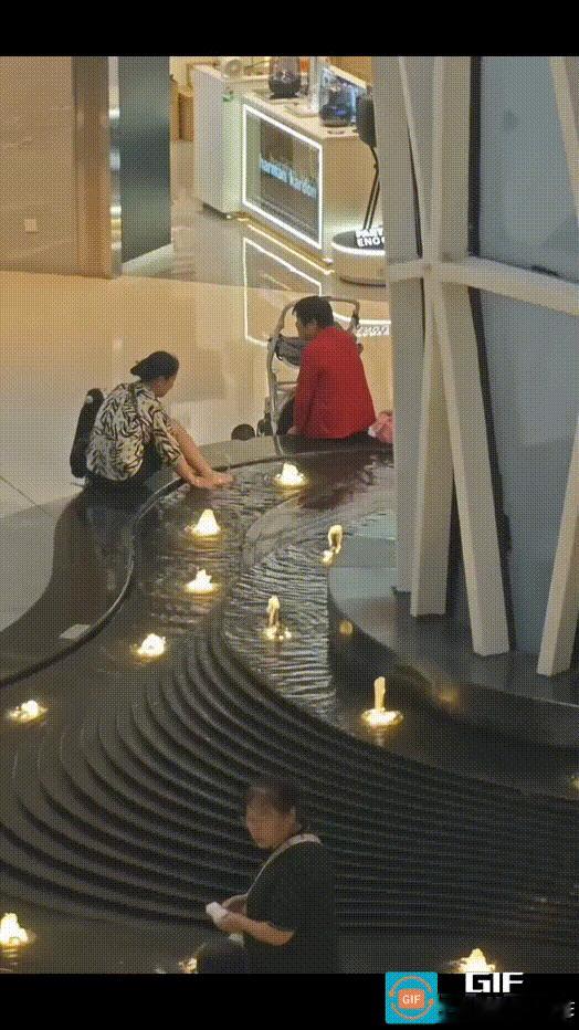 女子将商场喷泉水池当成自家洗脚盆，大模大样地将脚伸到水池中搓洗。
视频中，女子坐