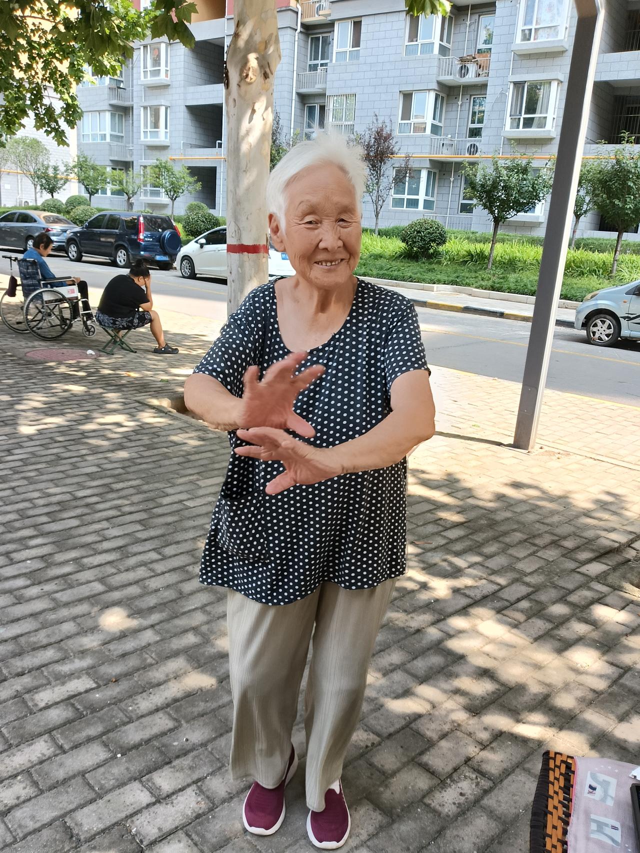 这是我们小区体育场，八十八岁的张大姐天天提个马扎，一手拿个収录机，边徒步走边听歌