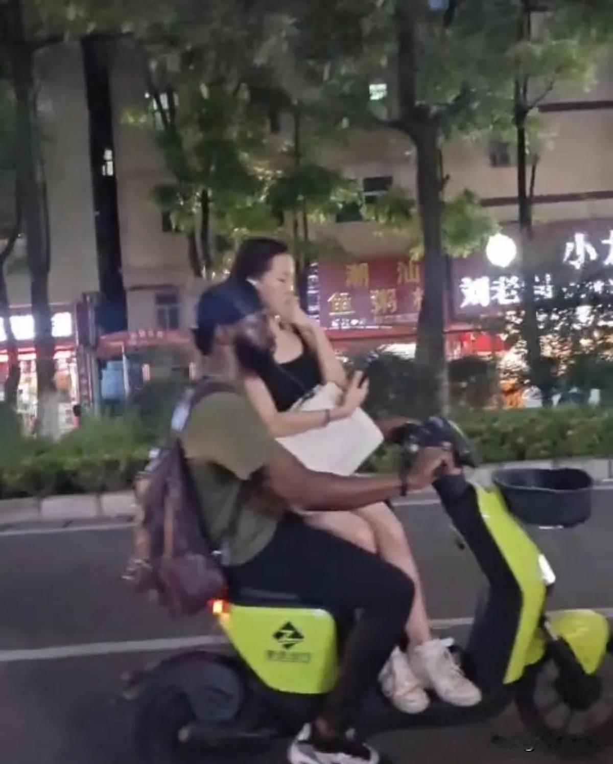 她居然还会不好意思？

一非洲男子骑电动车载个女生，路人拿手机拍，女生立马用手遮