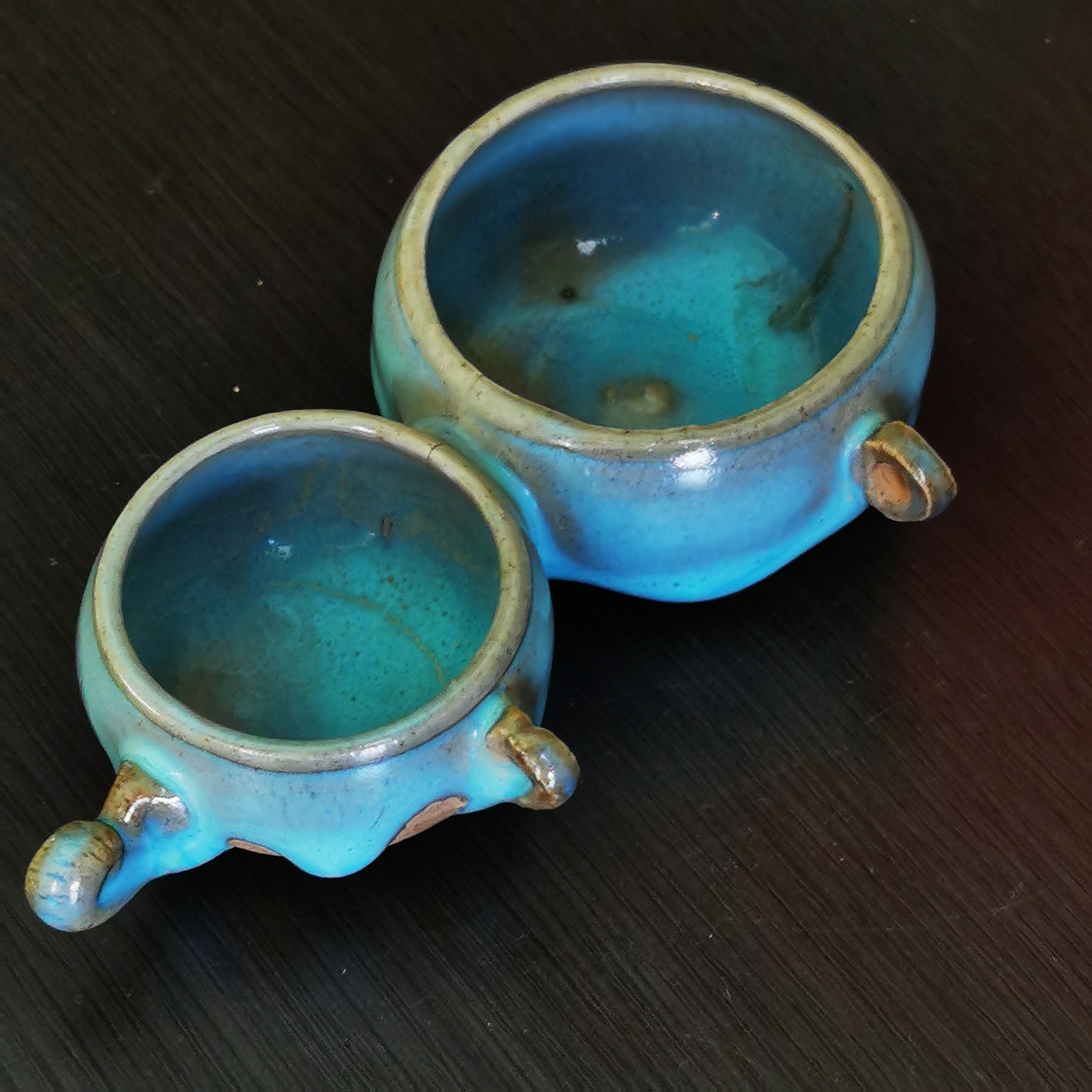 这款元代钧瓷双联鸟食罐，造型精致古朴，釉面温润如玉，其瓷胎质较宋代粗糙，但釉色滋